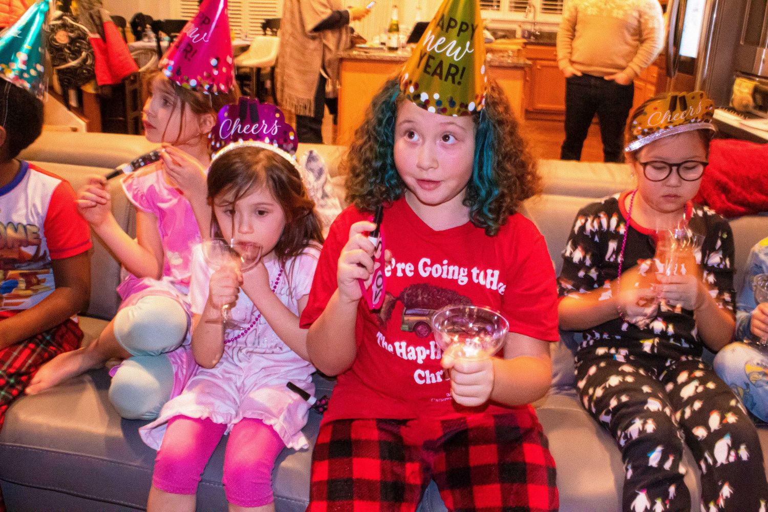 Kids celebrating with party horns and hats at a festive gathering.