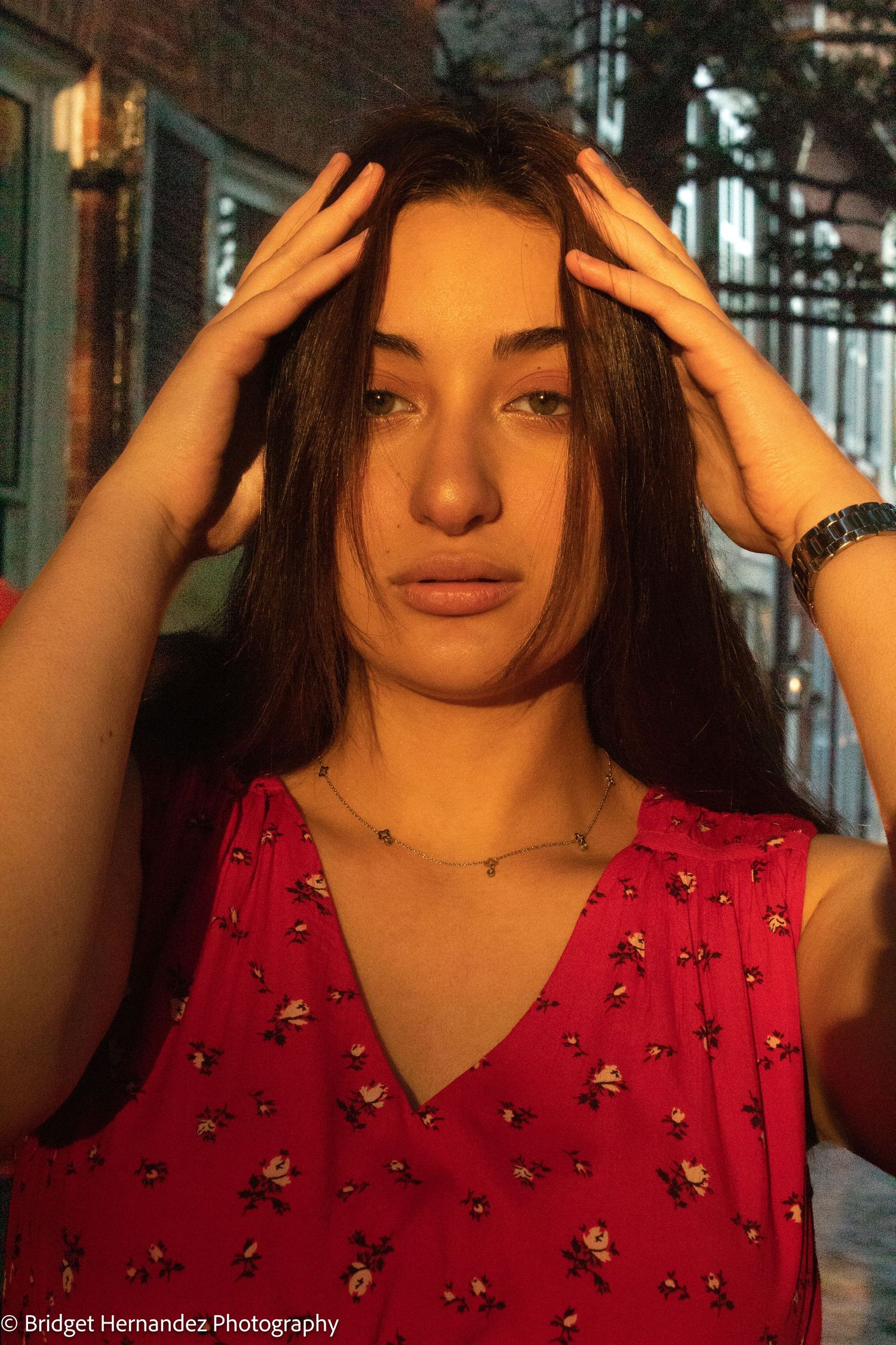 Sunset portrait session in a red patterned dress on historic brick streets.