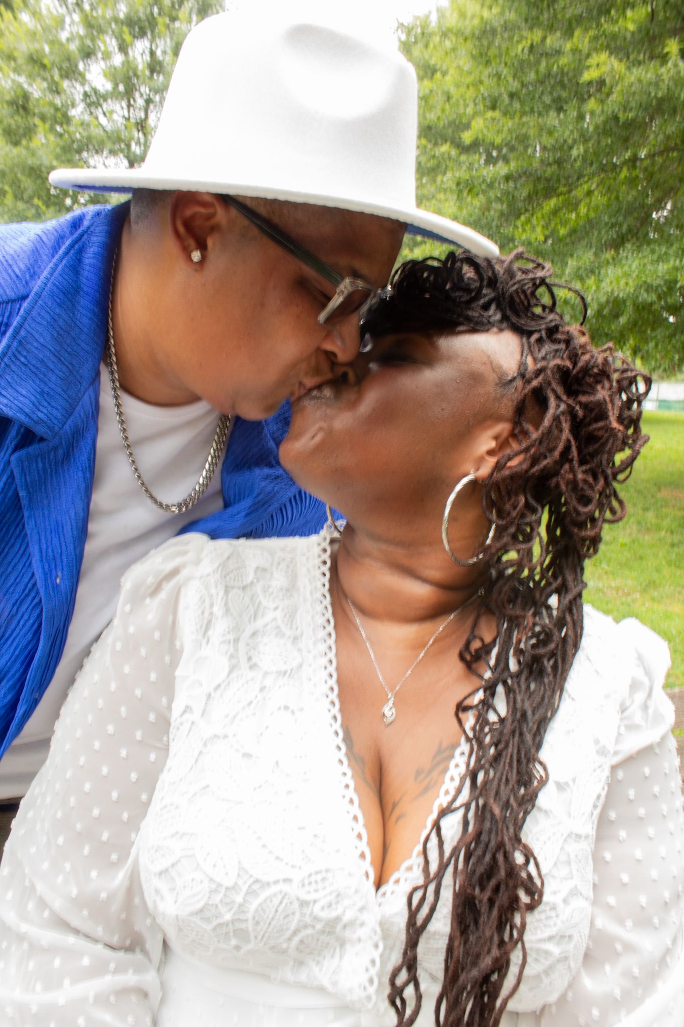 Intimate moment between couple in blue and white attire in park setting.