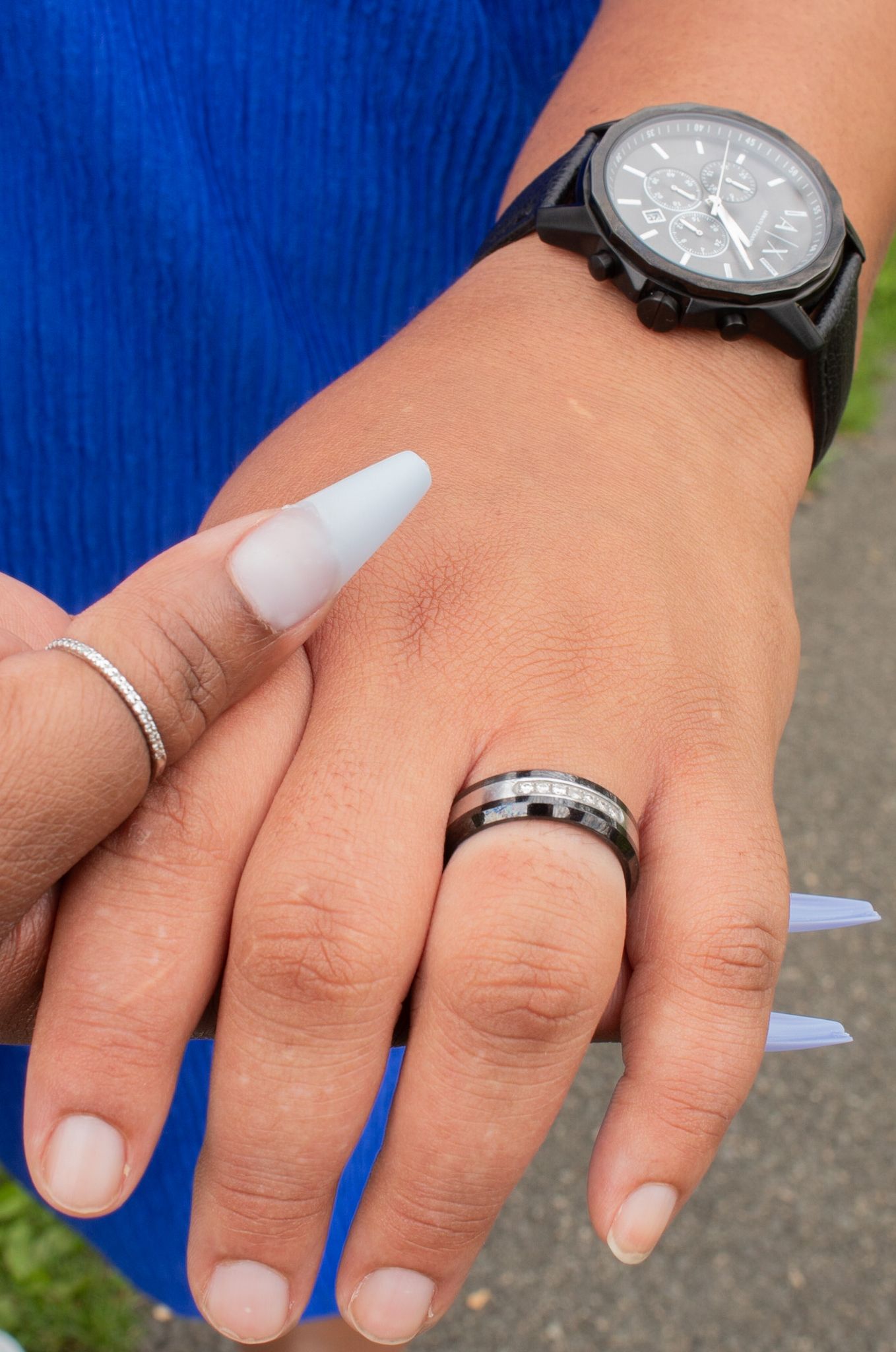 Detail shot of hands wearing silver rings and a watch with white manicured nails.