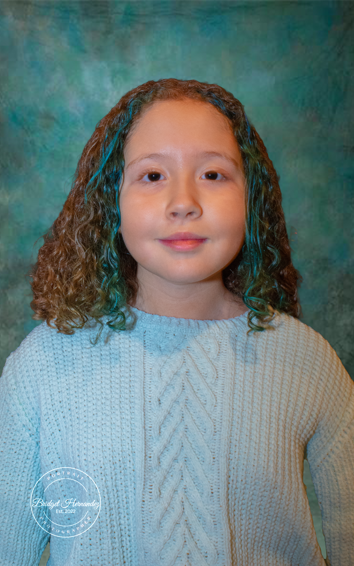 A child wearing a blue cable knit sweater poses against a teal backdrop in a portrait series showing different facial expressions.