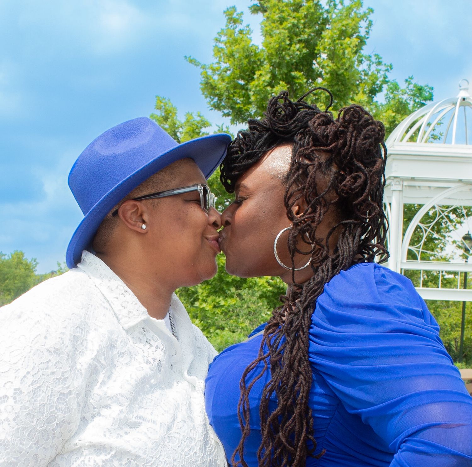 Couple sharing an affectionate moment near white gazebo on waterfront deck.