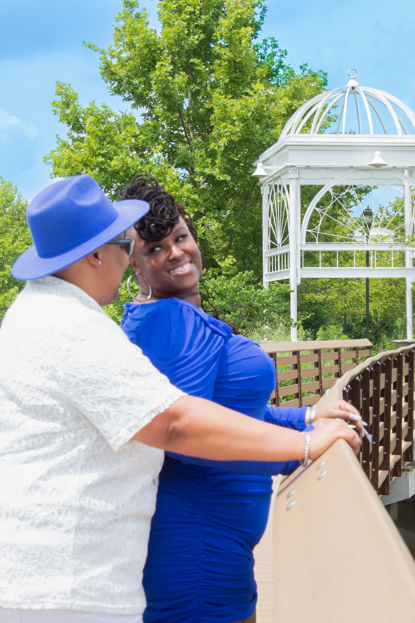 White gazebo frames scenic boardwalk view with couple in blue and white outfits.