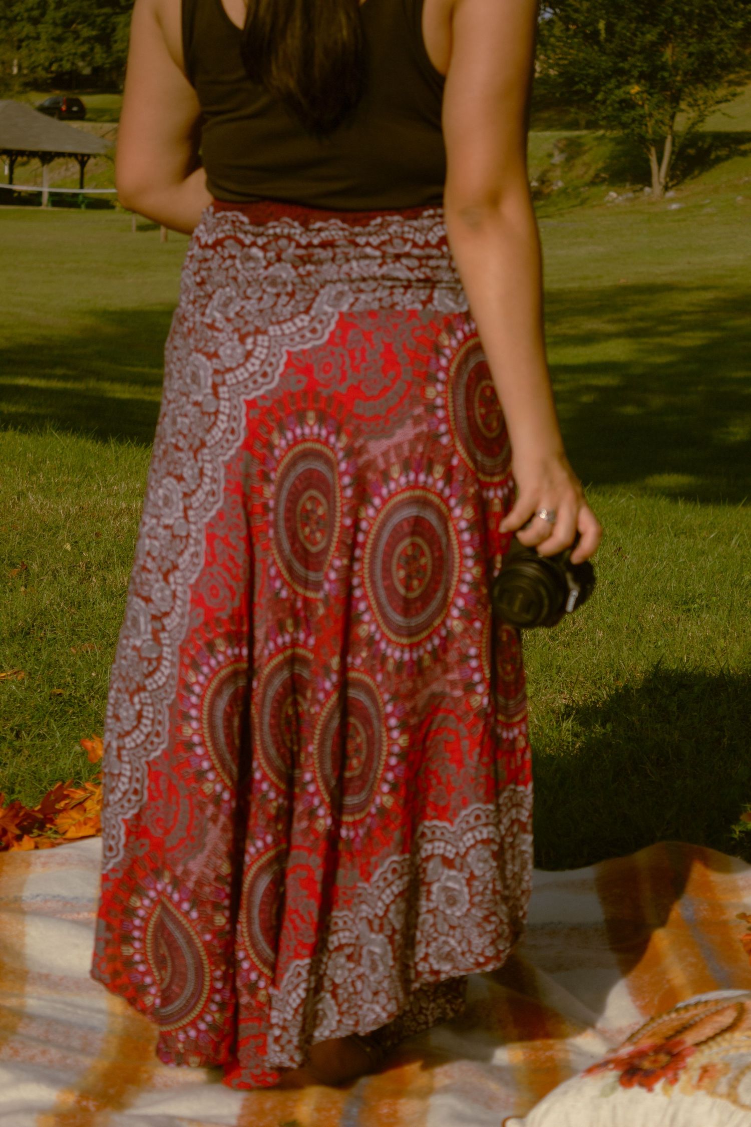 A flowing red and white paisley patterned skirt is shown in a series of outdoor photos against a green background.