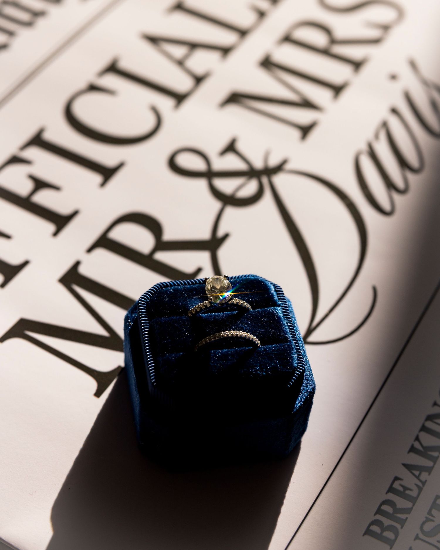 Diamond engagement ring in blue velvet box on Mr. and Mrs. newspaper announcement.