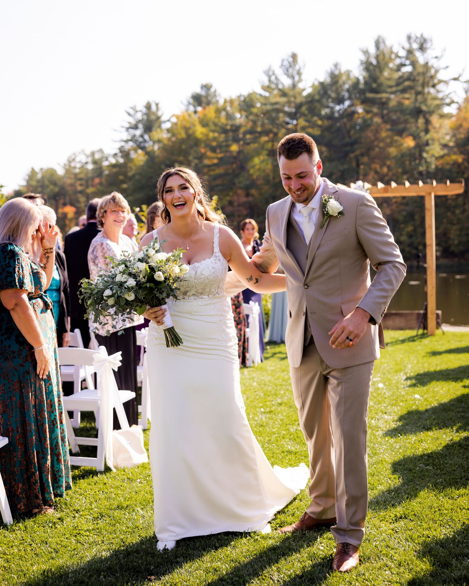 Joyful bride and groom walking back down the aisle after outdoor wedding ceremony on lawn.