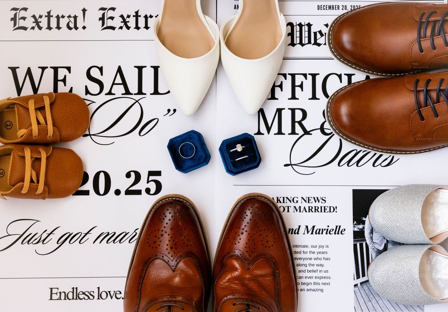 A flat lay of wedding shoes, rings in a blue velvet box, and a custom newspaper announcement for a wedding.