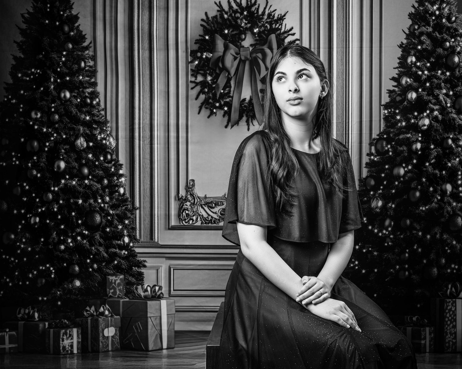 A black and white portrait series of someone in elegant poses against a backdrop with ornate molding and decorative trees.