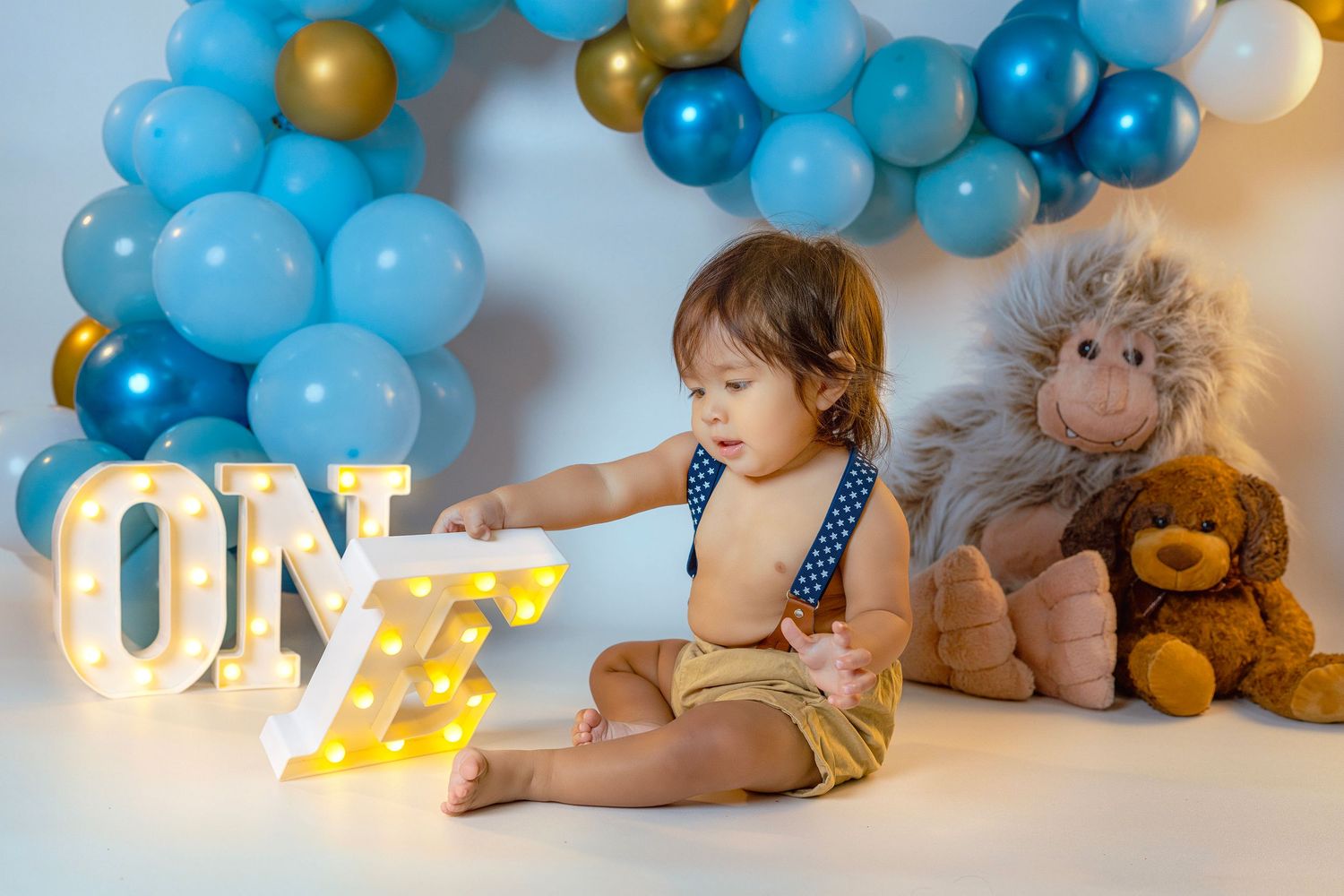 A series of baby photos with blue and gold balloon decorations showing monthly growth milestones during the first year.