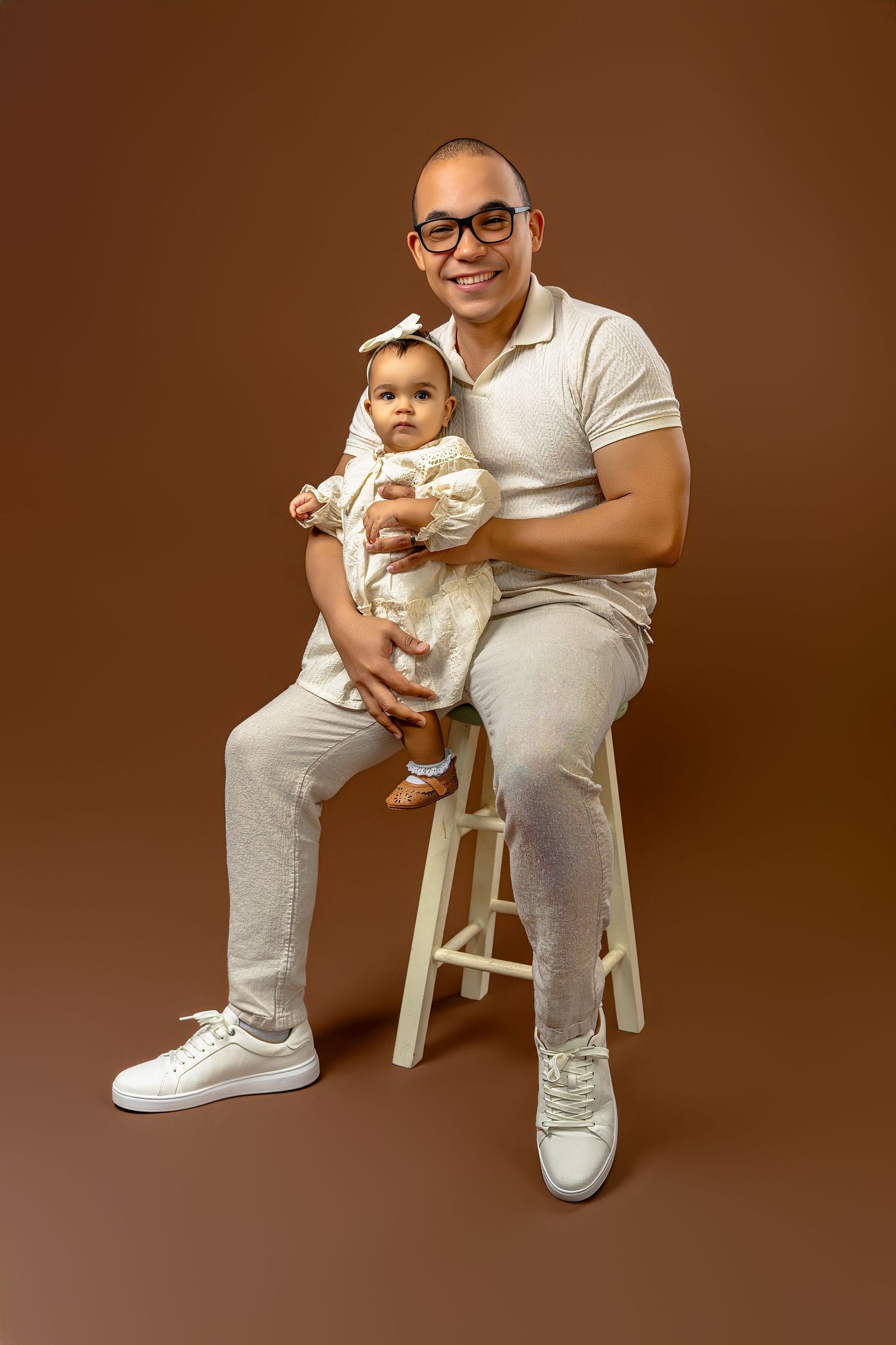 A series of photos showing someone in white clothing sitting on a stool while holding a small white dog.