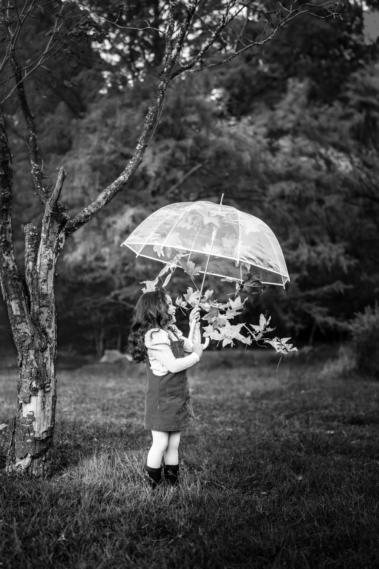 A whimsical black and white photo series showing a figure floating with an umbrella in a dreamy outdoor setting.