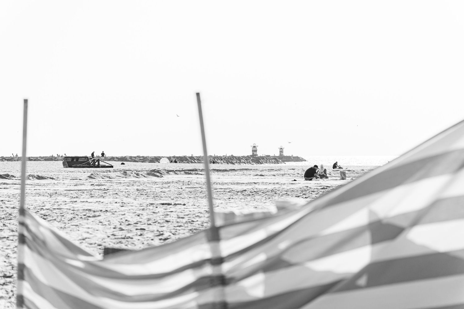 Wave patterns in white fabric against a bright sky create a dramatic rippling effect near a body of water.