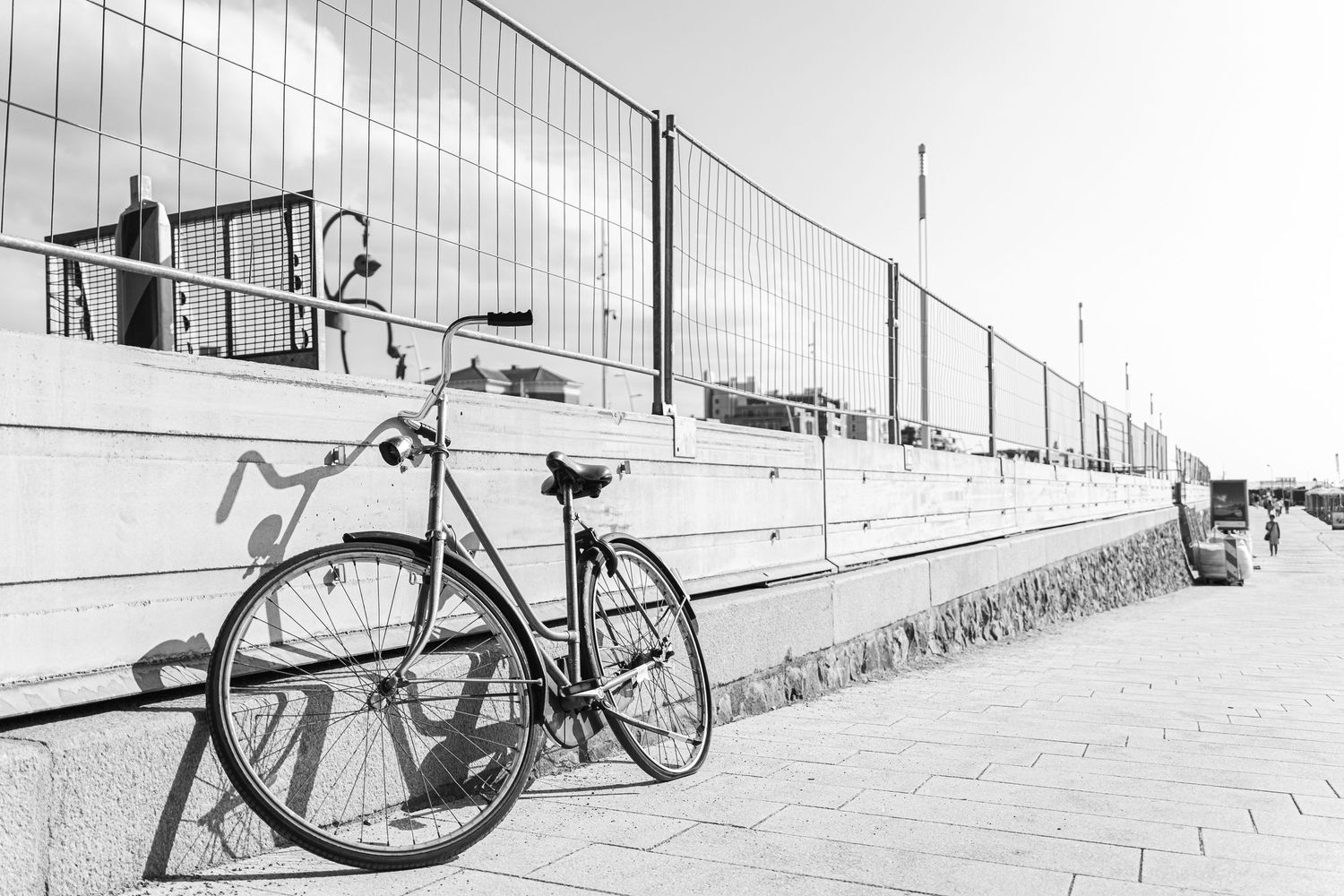A receding black and white composition of multiple bikes parked along a wall creating a minimalist perspective shot.