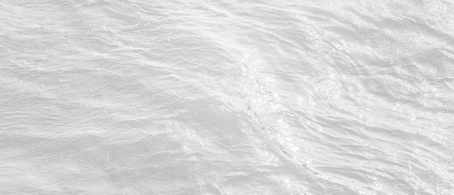 Aerial view showing ocean waves with white foam patterns rolling across dark blue waters.