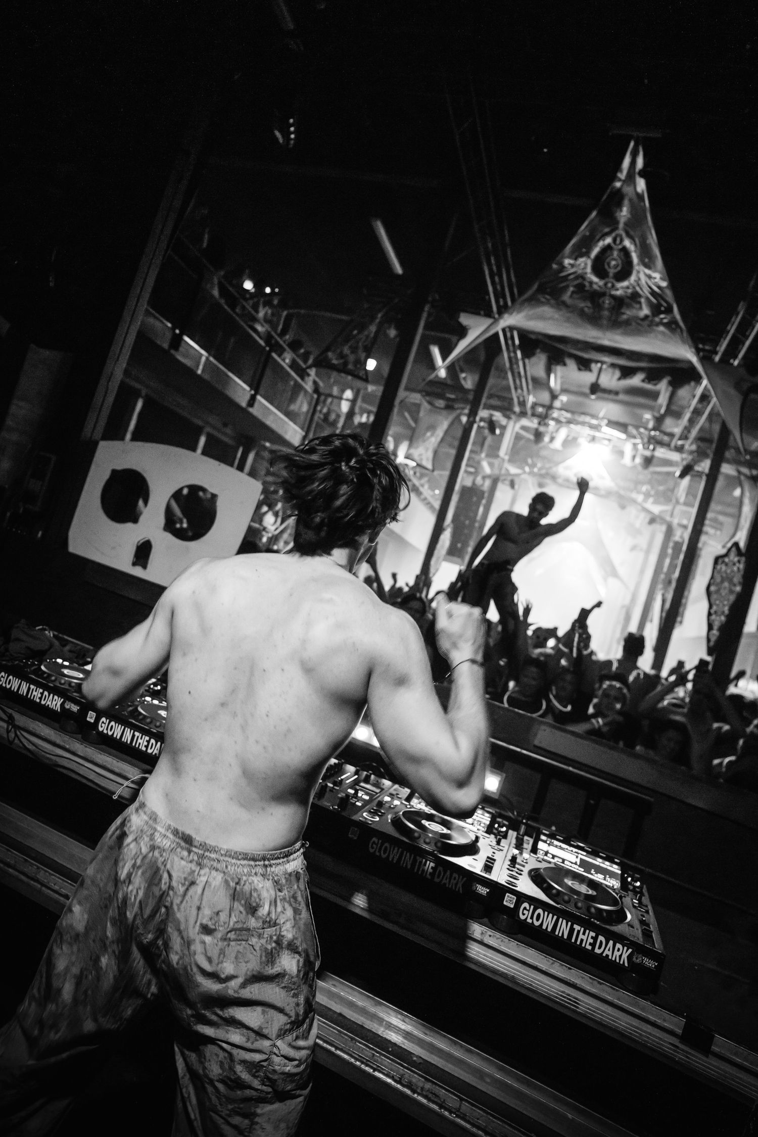 A black and white photo sequence shows a shirtless person in camouflage pants dancing at a bar or club venue.