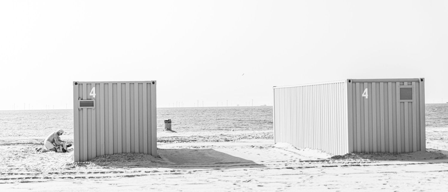 A row of industrial metal storage containers stands in a snowy winter landscape against an overcast sky.