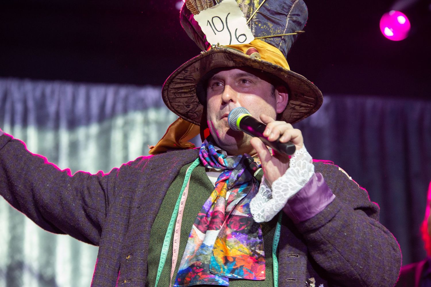 Person wearing a cowboy hat performs on stage with colorful lights in the background during a musical performance.