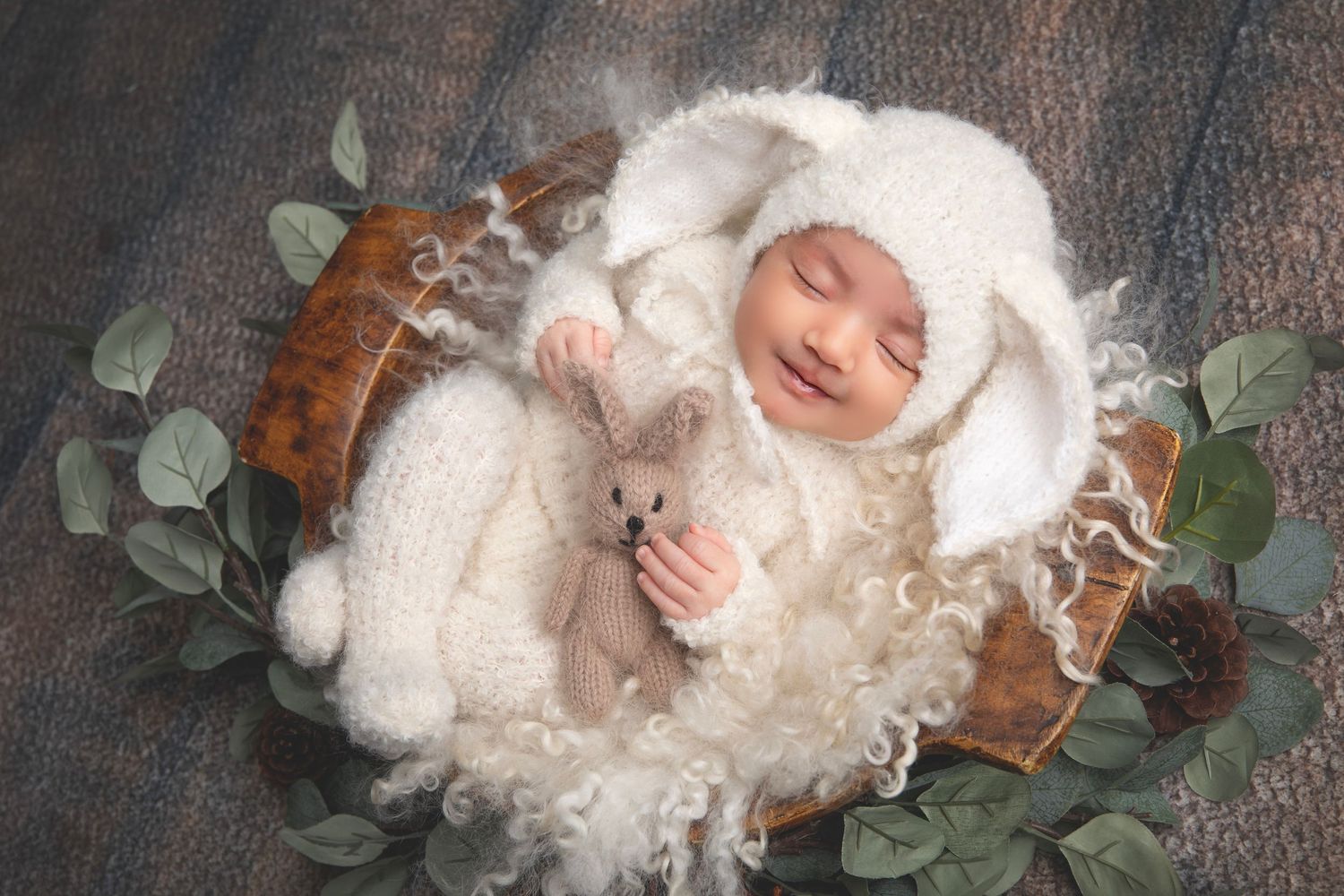 Delicate newborn portrait series with baby nestled in white fluff and eucalyptus leaves.