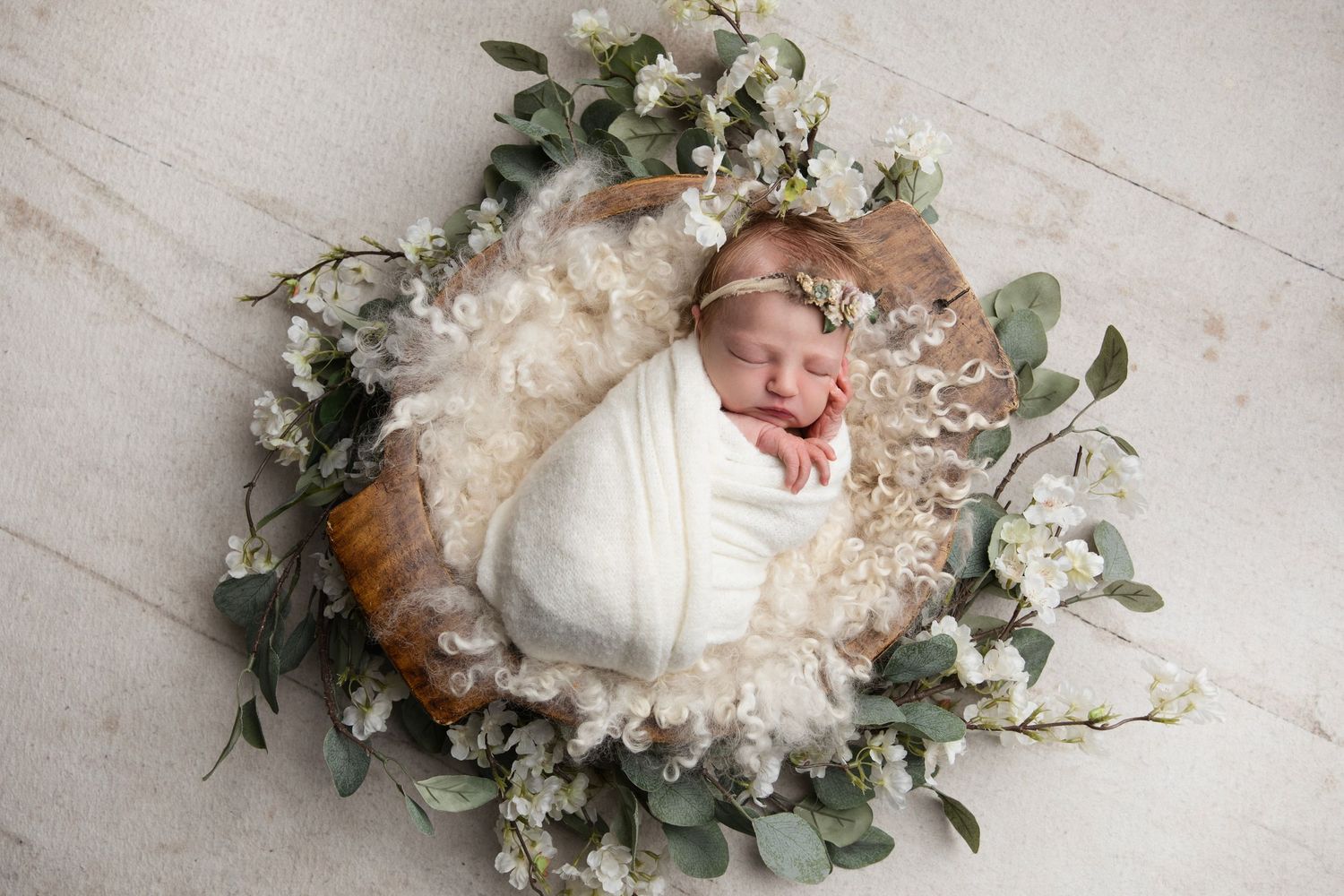 Delicate white and pink peony floral arrangement with eucalyptus leaves on a light textured surface.