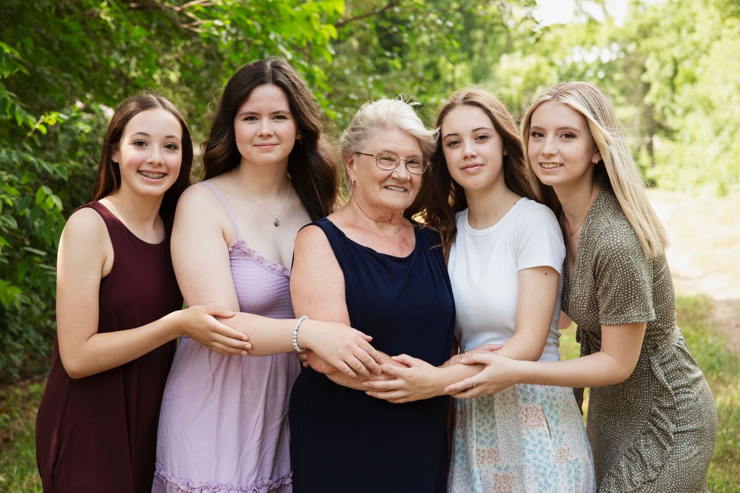 Multigenerational portrait of women and girls embracing outdoors in summer.
