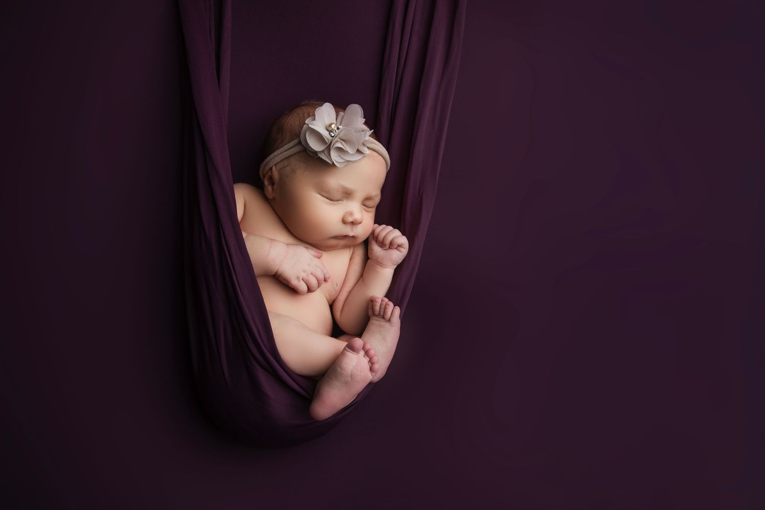 Artistic newborn photography sequence showing baby wrapped in deep purple fabric.