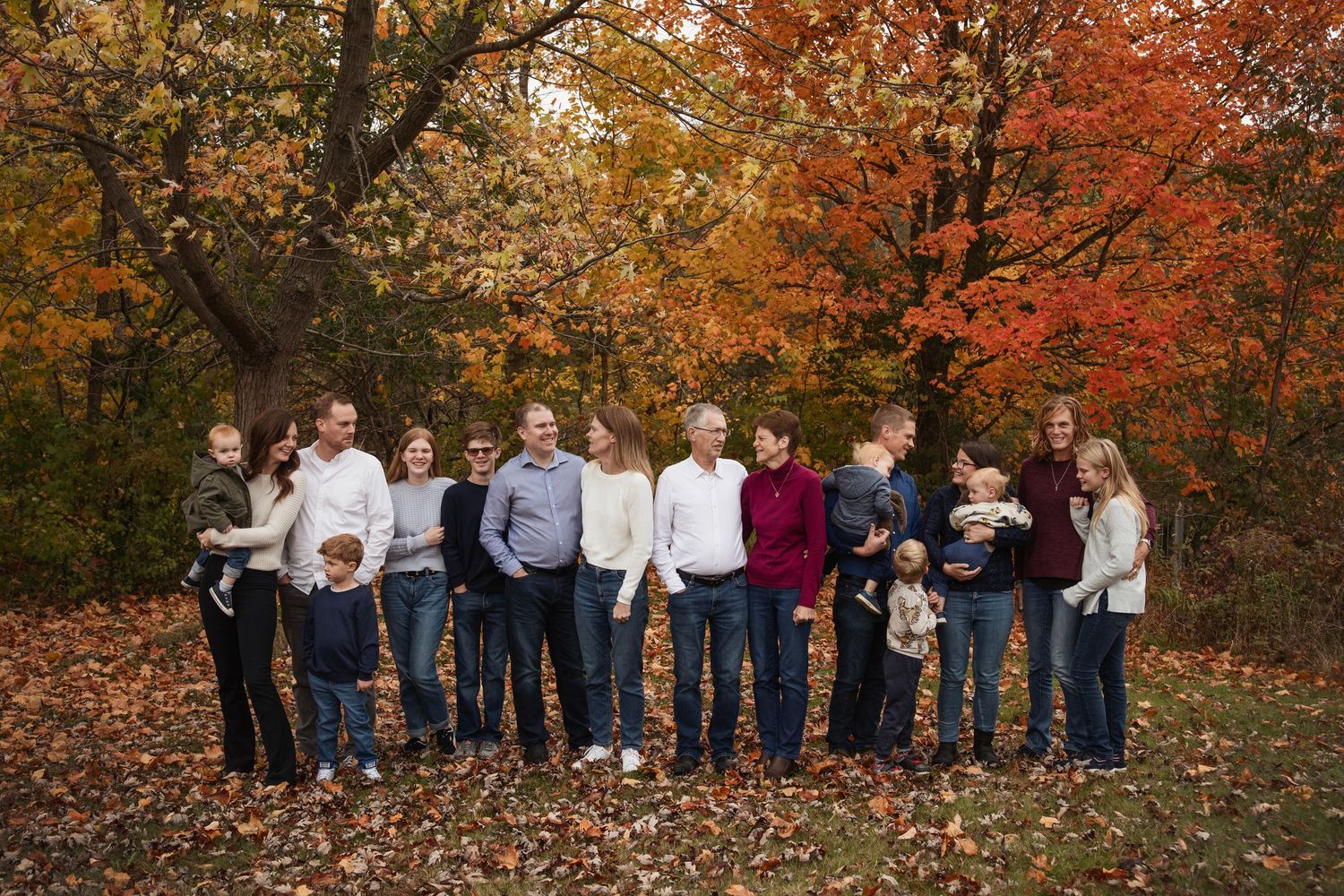 Extended family portrait against vibrant fall foliage background.