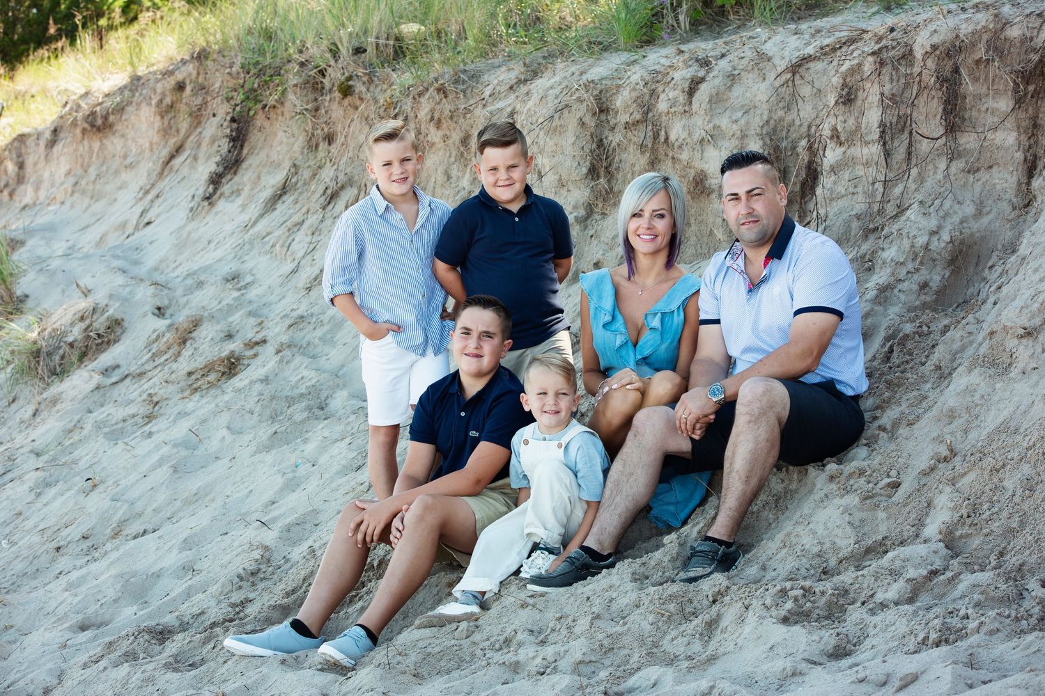 Group sitting together on sandy embankment during outdoor photo session.