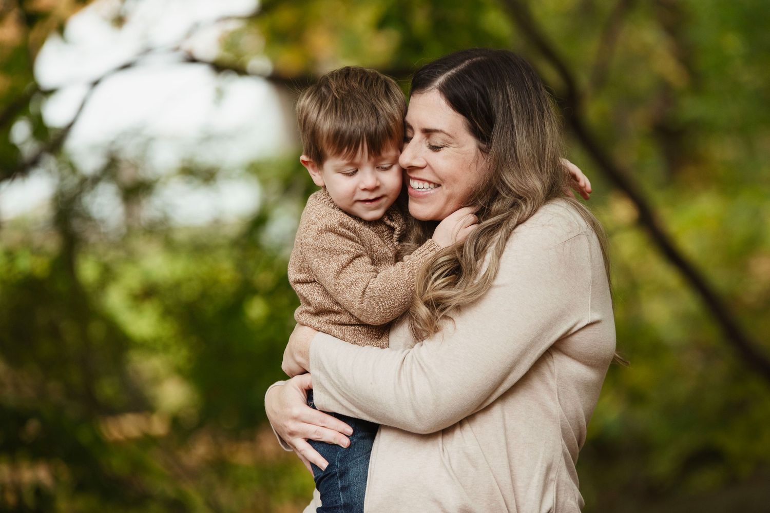 Family portrait series in autumn setting showing intimate moments between parent and child.