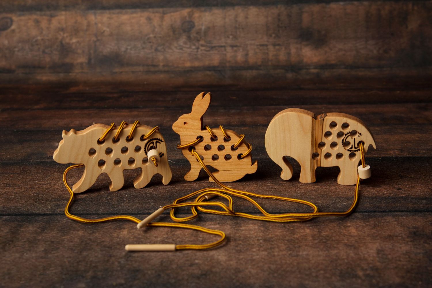 Wooden pull-along toy featuring three laser-cut animals - hedgehog, rabbit, and elephant - connected by a string on rustic wood.