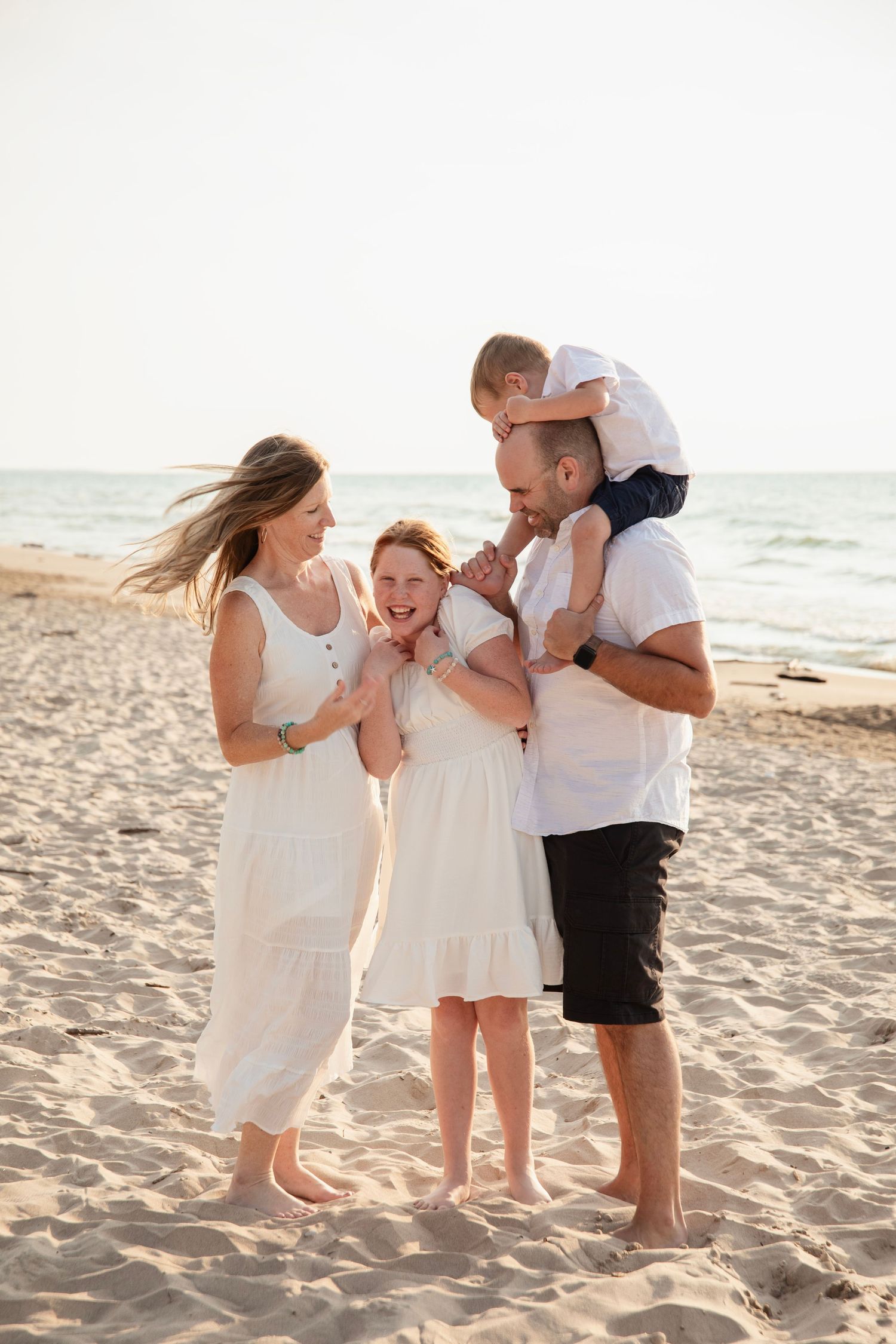 A happy family shares joyful moments together on a sunny beach during golden hour.