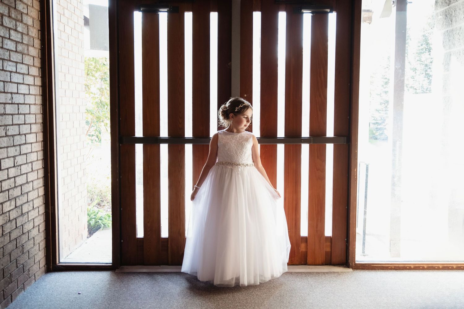 Interior church shots showing wooden doors and brick walls with natural lighting and a girl in a first communion dress.