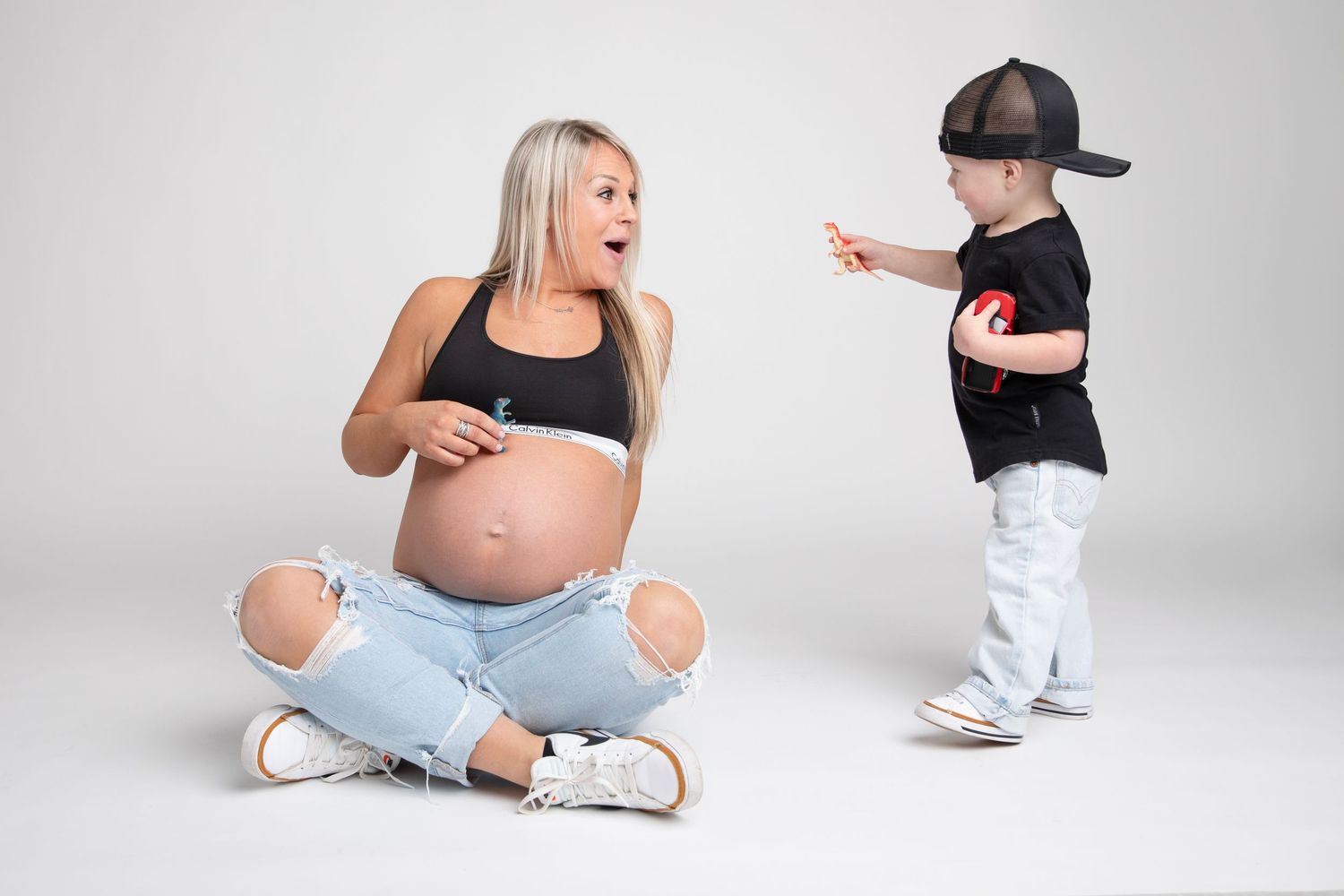 A series of casual maternity poses showing a mother and son sitting on the floor in a bright studio setting.