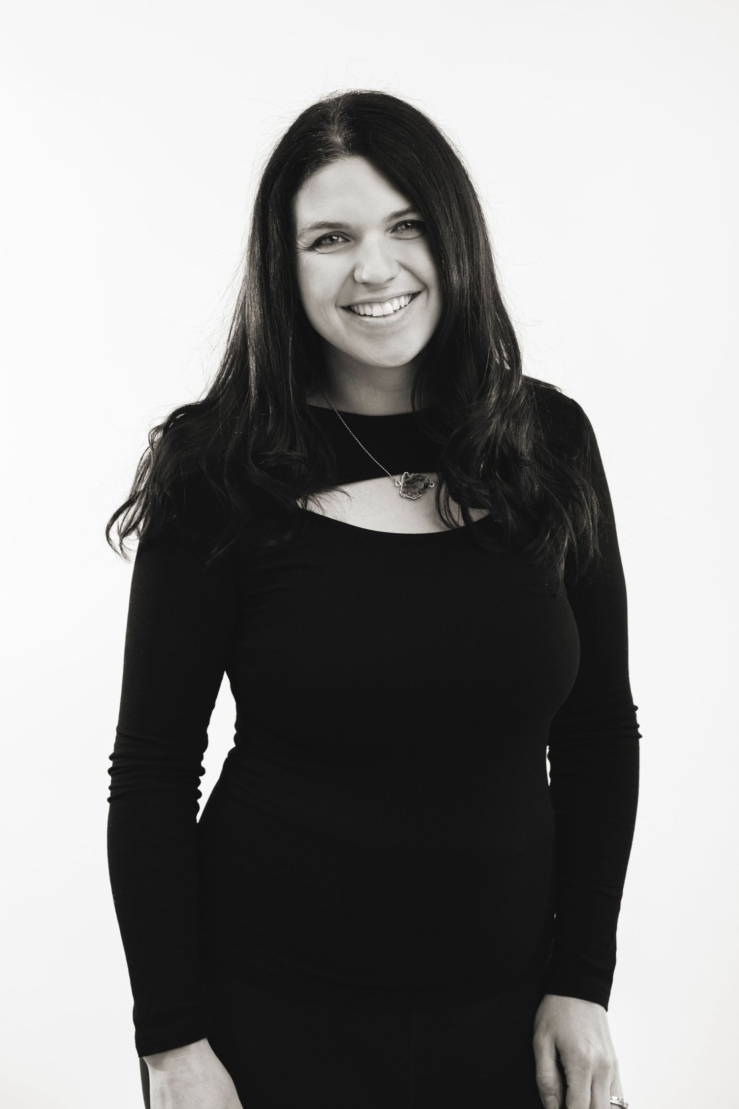 Black and white portrait of Amanda Kopcic with long dark hair wearing a black long-sleeved top against a white background.