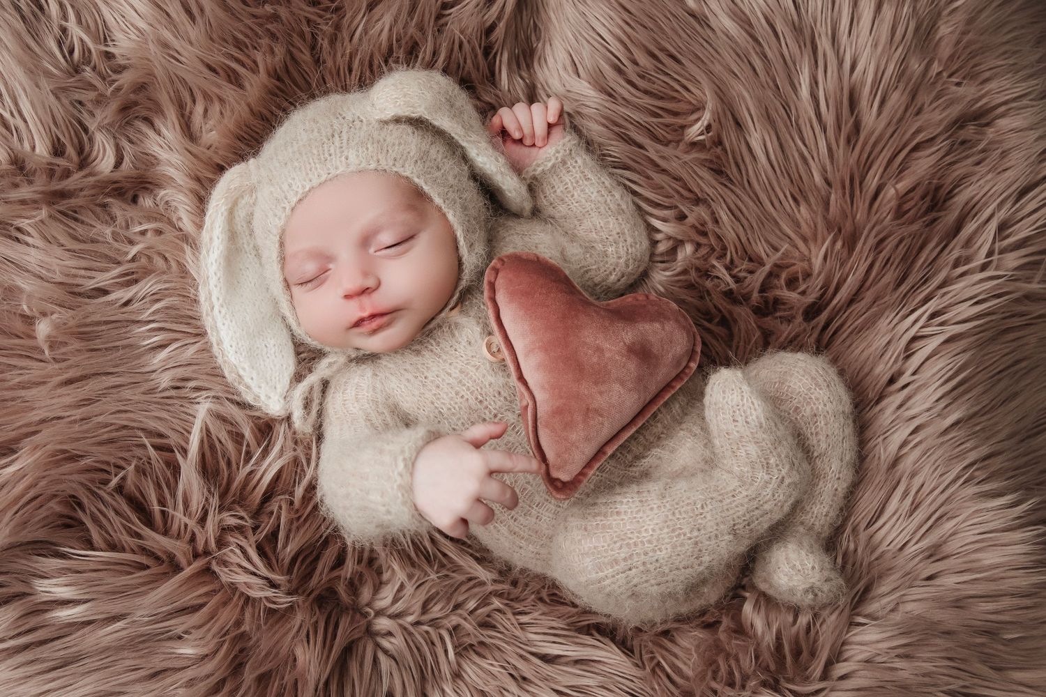 Baby sleeping on plush brown fur blanket in cozy neutral tones.
