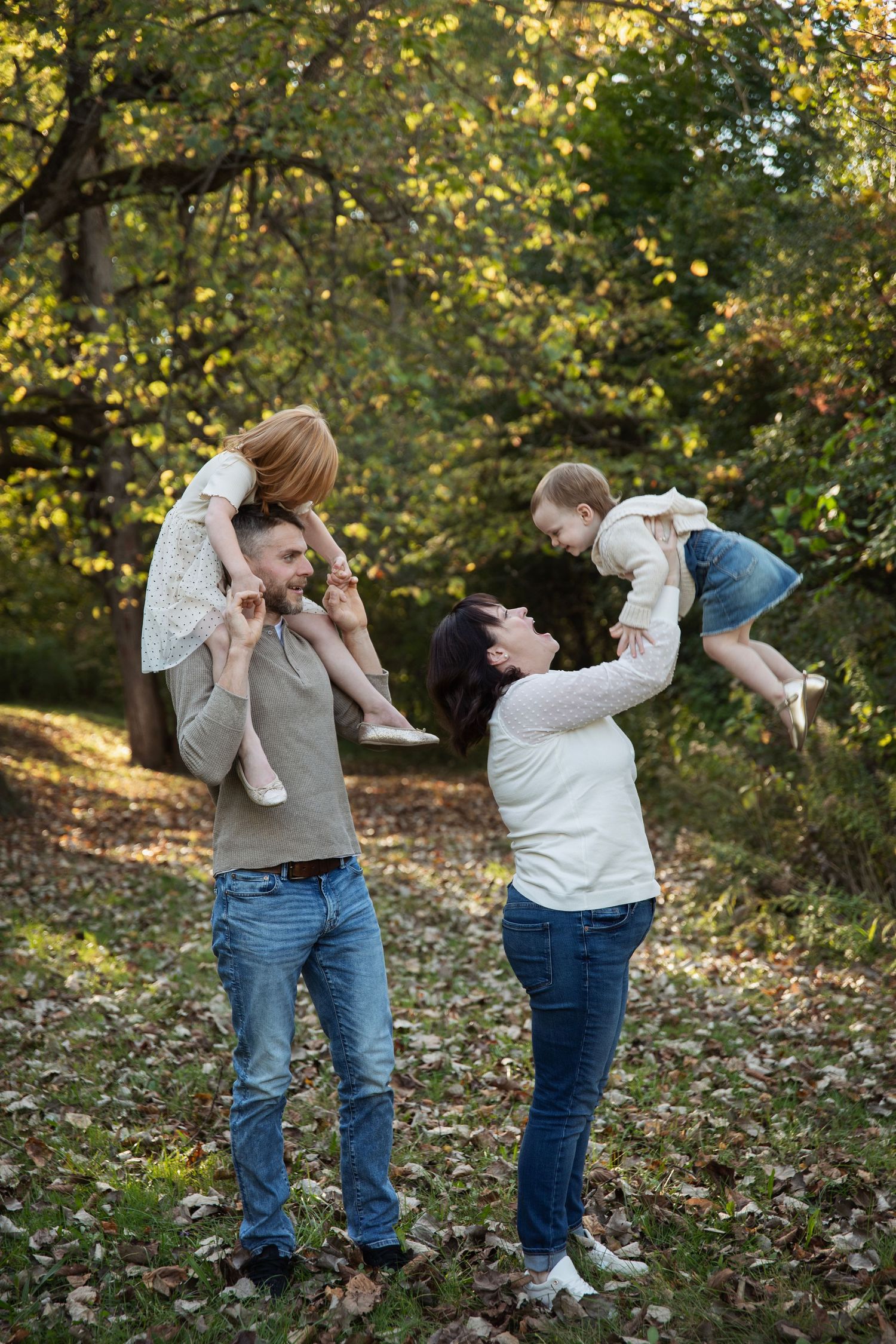 Family enjoying a playful moment together in an autumn forest setting.