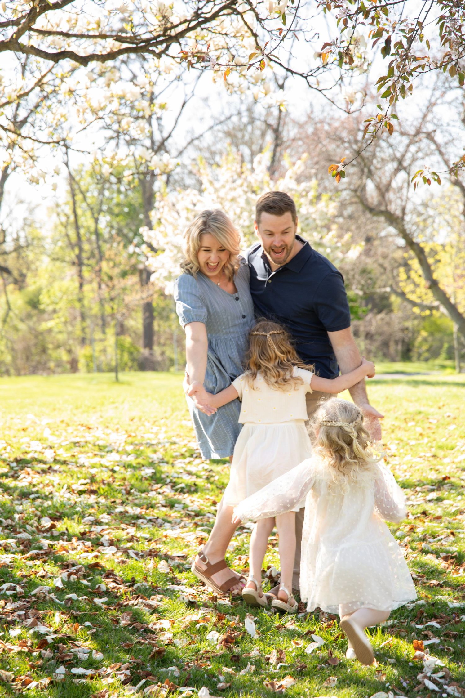 Family playing together in a fall park with yellow leaves scattered on the ground.