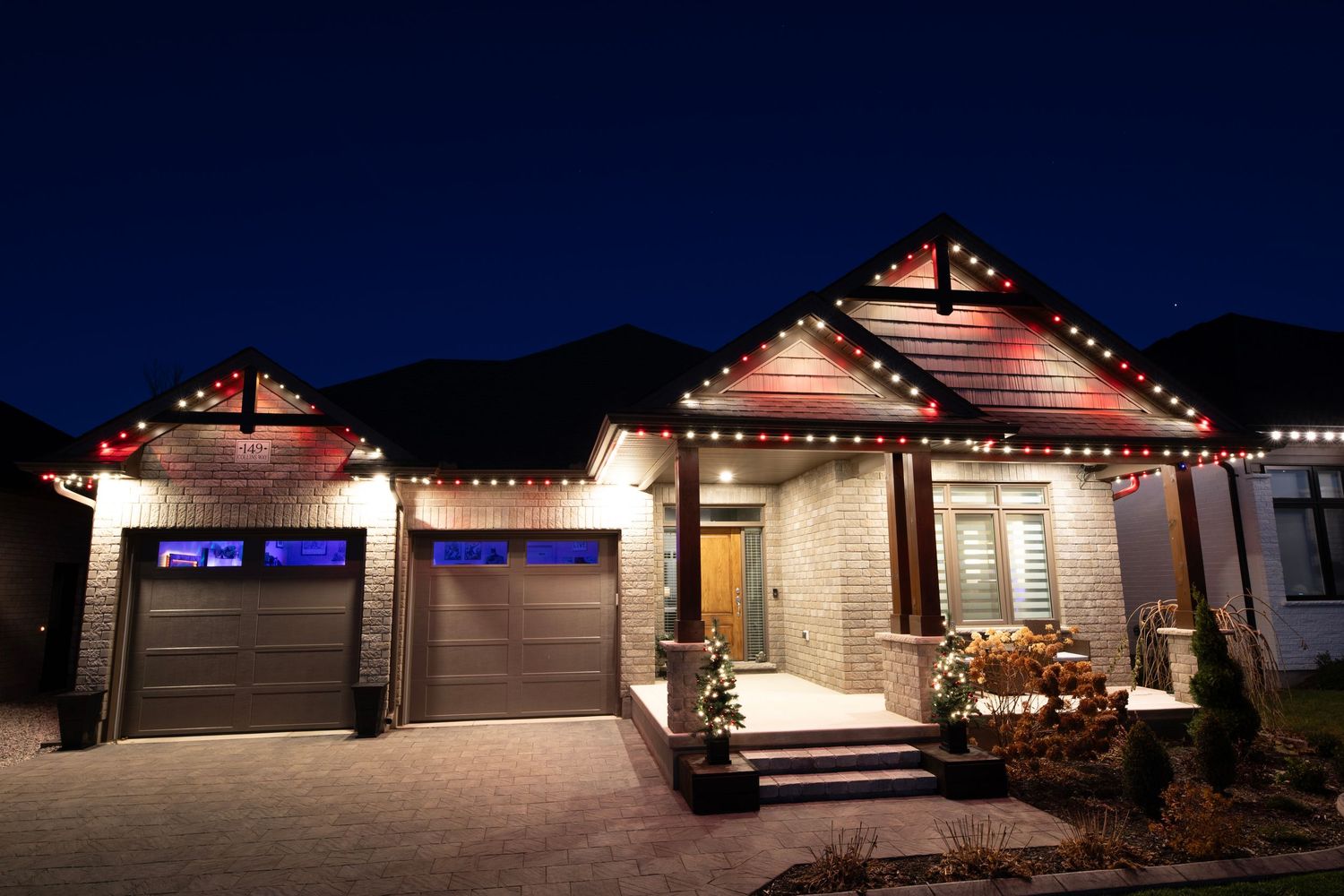 Exterior night view of modern houses with illuminated garages and decorative outdoor lighting.