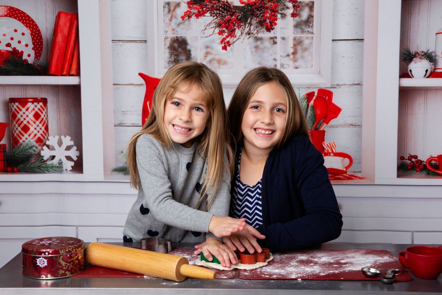Two people lying on a white floor with red and white holiday decorations in a studio setting.