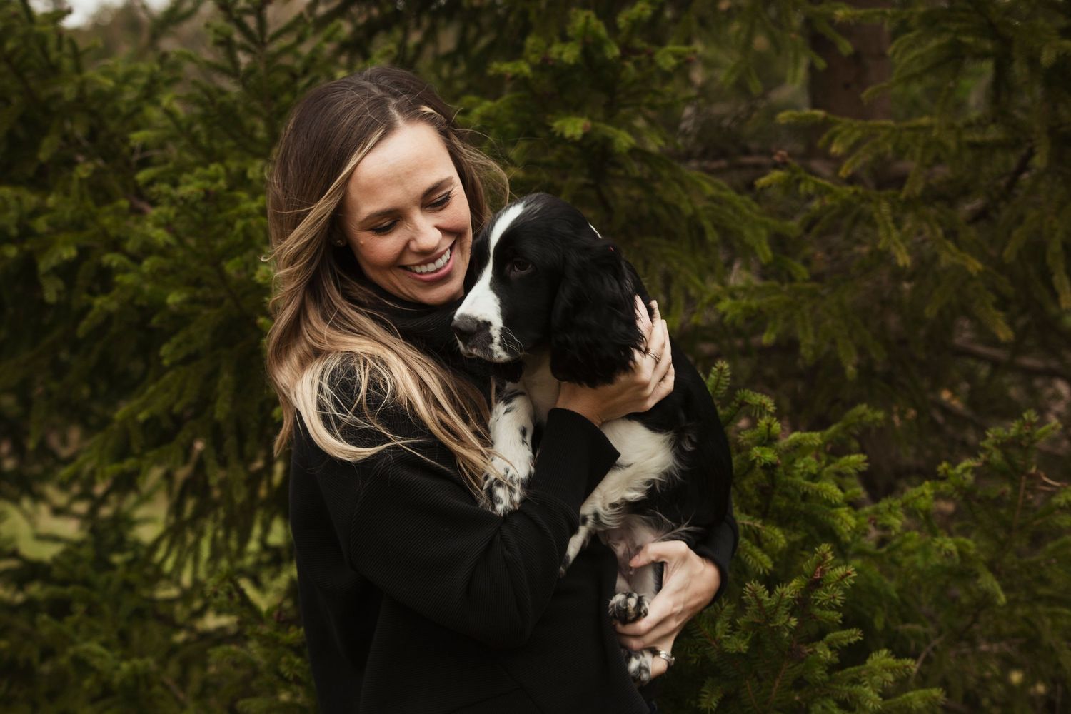 Black and white dog being lovingly held close in outdoor fall setting.