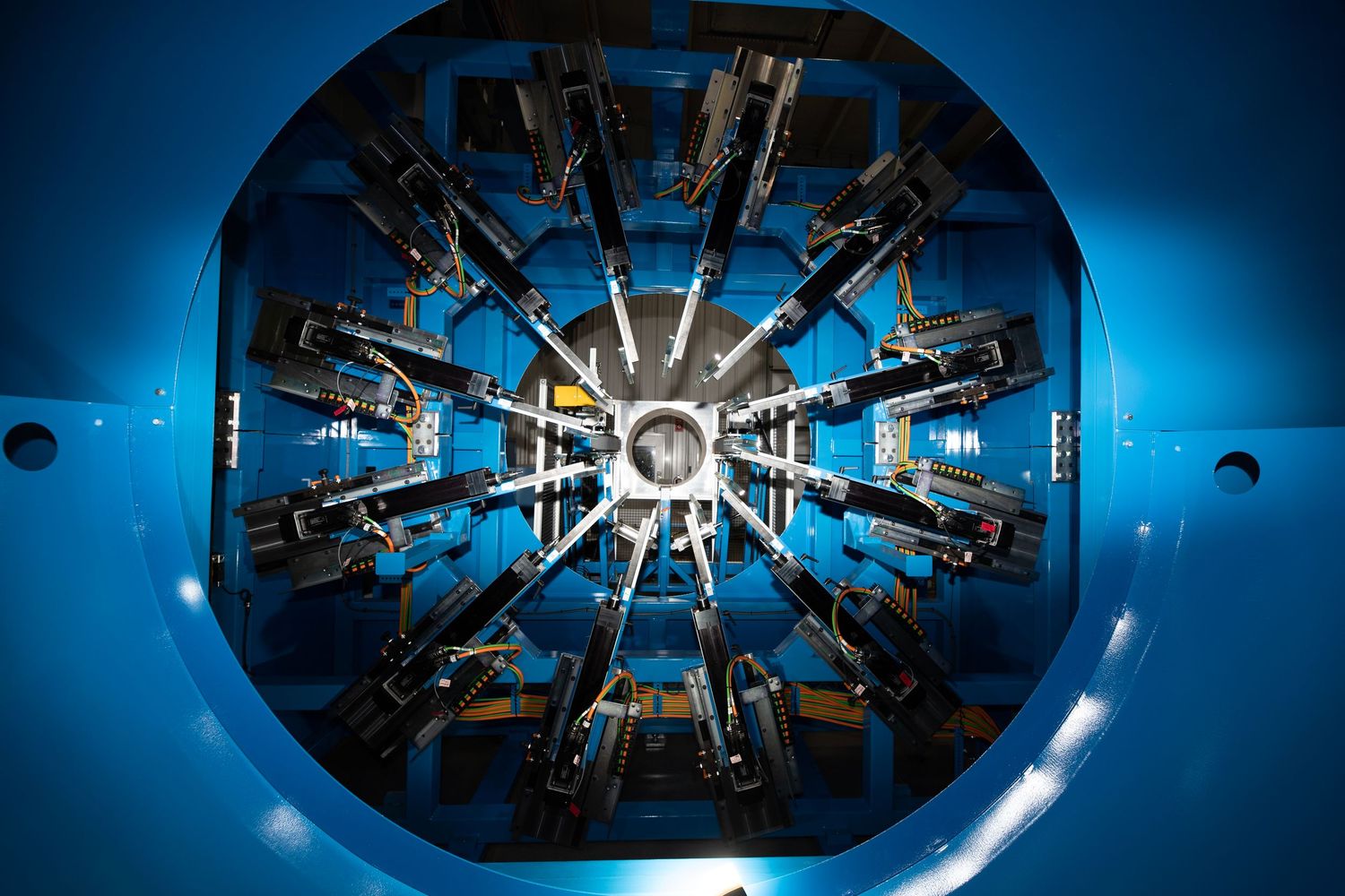 Radial view of a circular machinery component with multiple metal arms arranged symmetrically against a blue background.