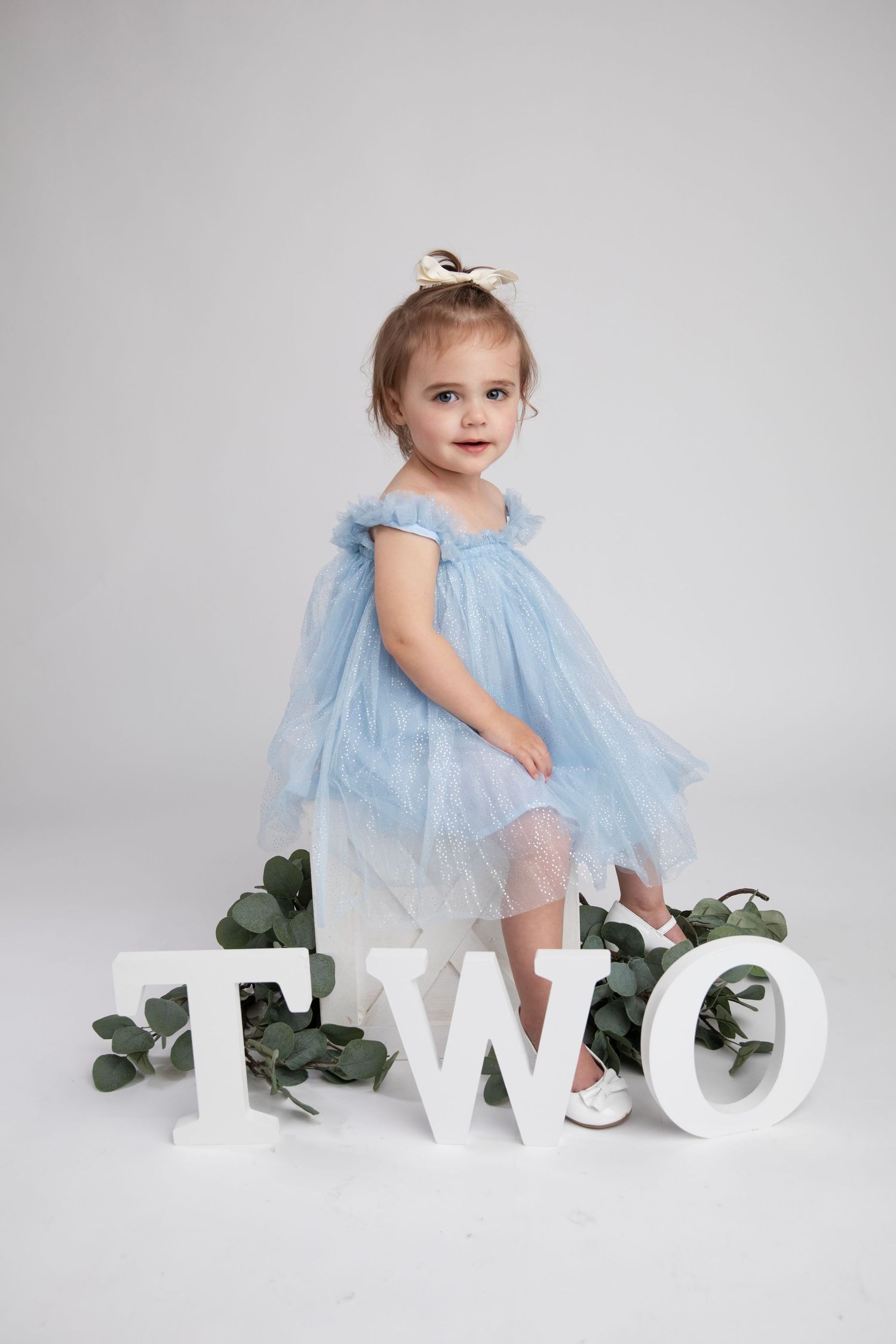 Birthday photoshoot with child in blue dress posing with white TWO letters.