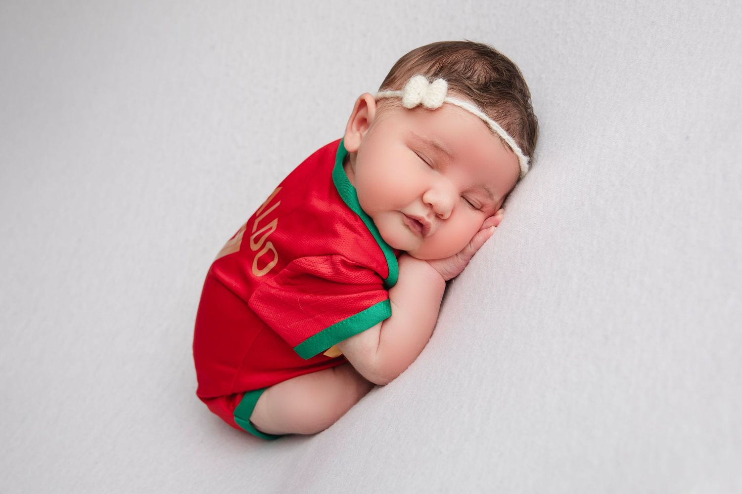 Newborn photo series featuring festive red and green holiday-themed outfit.