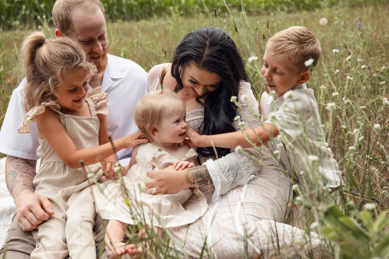 An adult and child share a joyful moment while playing in a field of white wildflowers on a sunny summer day.