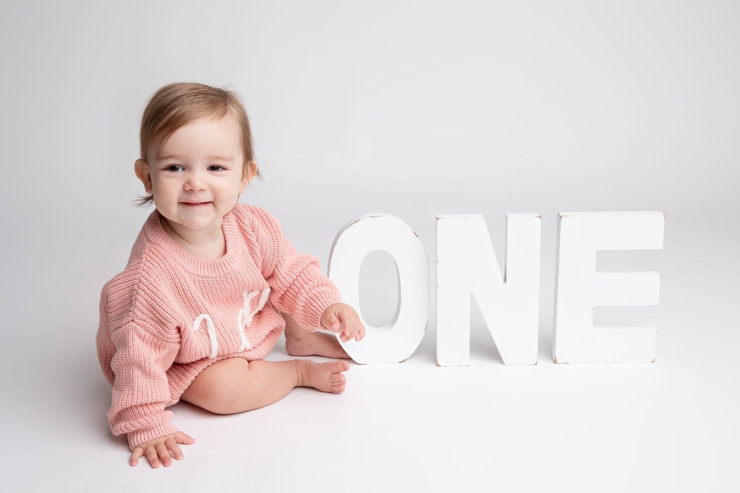Multiple shots of a pink knit sweater with text against a white background for a minimalistic look with the main focus on the child.