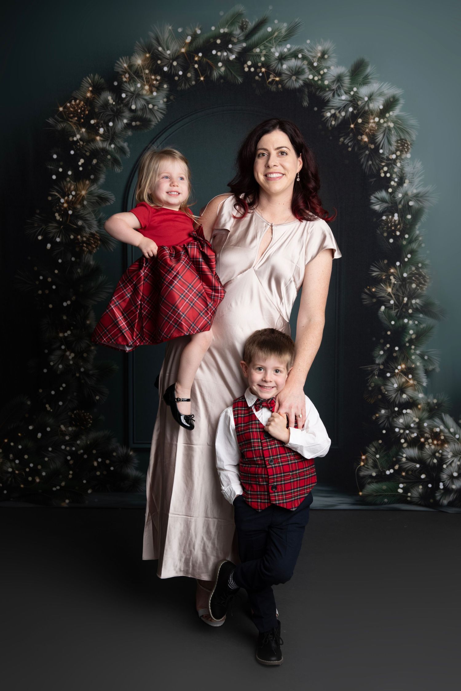 A series of holiday portraits against a dark backdrop with twinkling lights and festive greenery decorations.