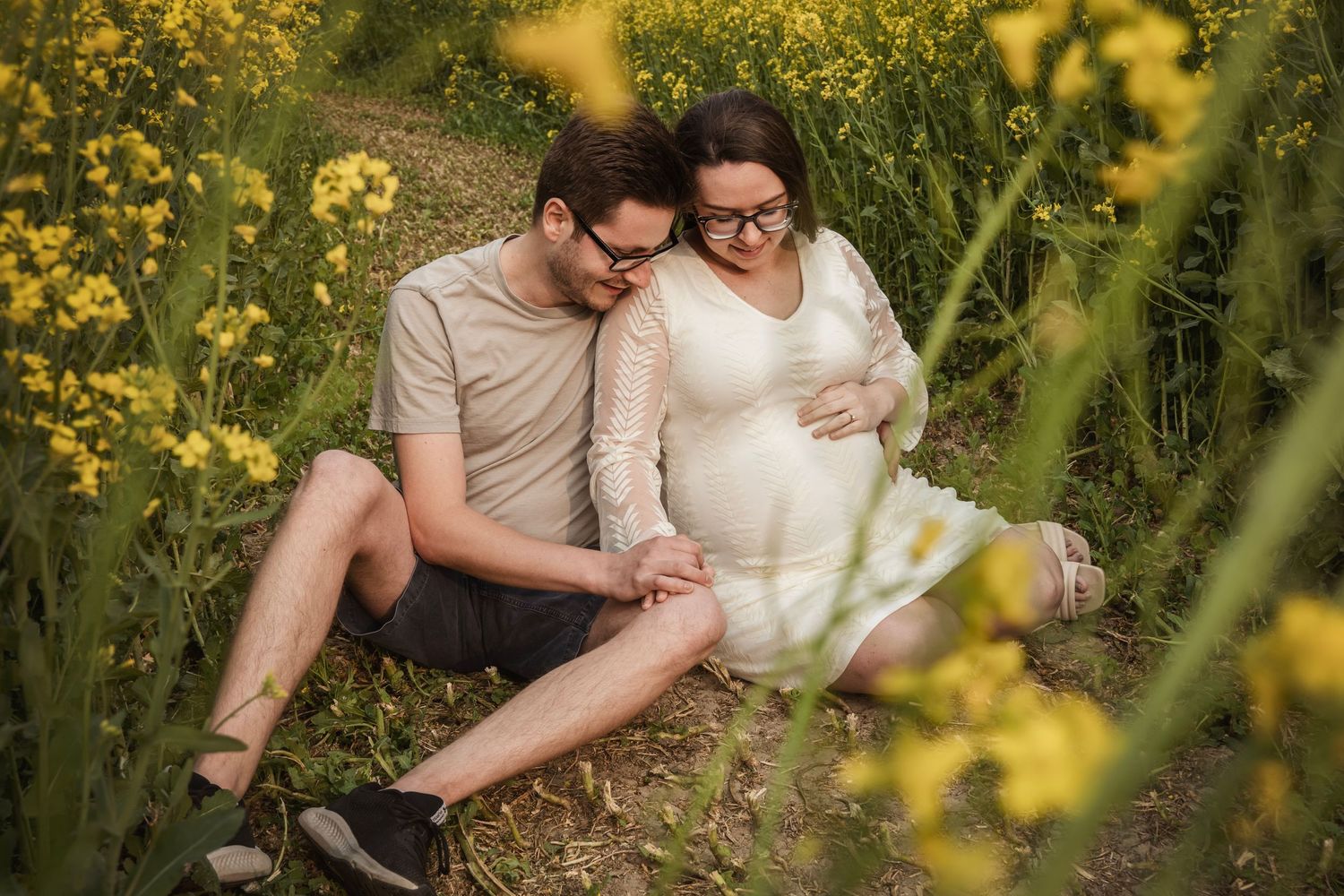Romantic couple embraces among blooming yellow flowers in a meadow during golden hour.