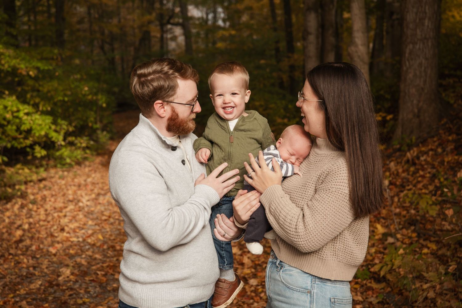 Young family sharing a playful moment together in an autumn forest setting.
