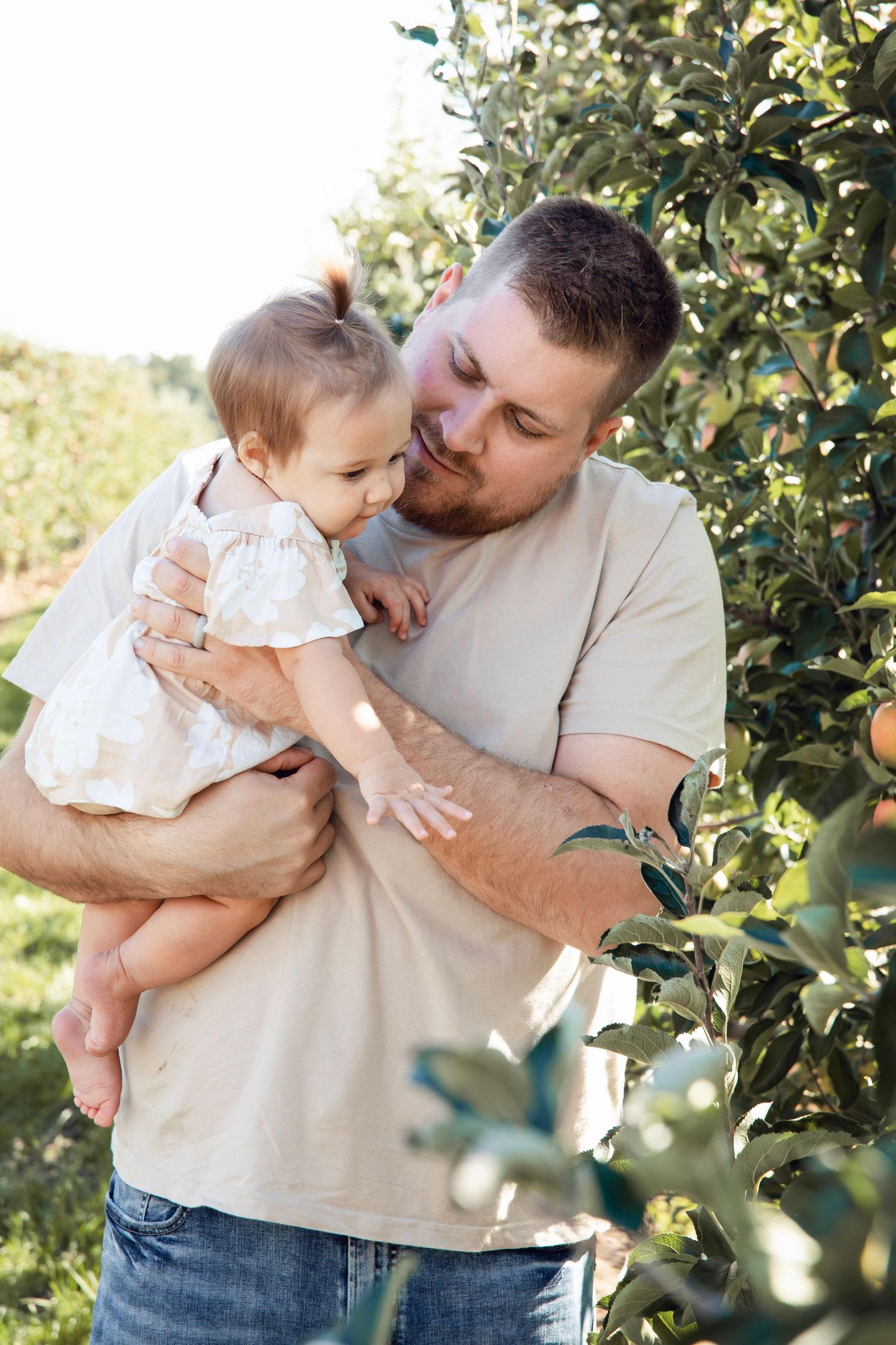 Tender moment between parent and child among apple trees in an orchard.