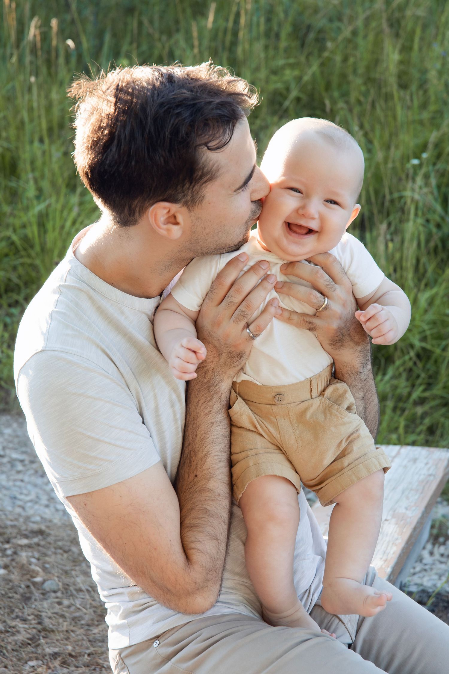 Tender moment between parent and baby on a sunny day in tall grass.