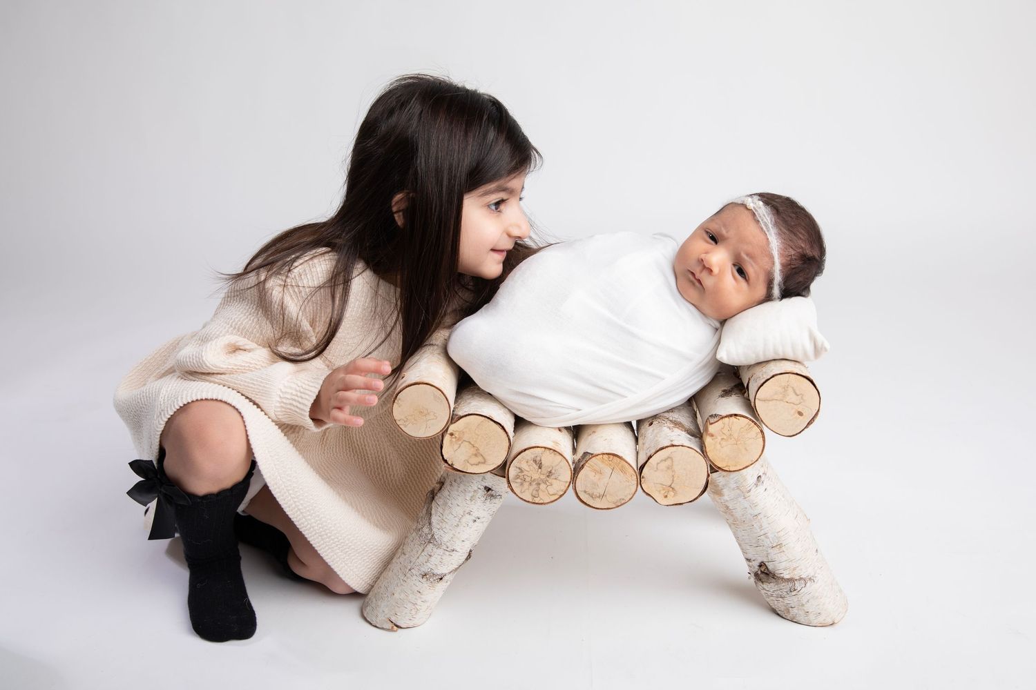 Minimalist series showing an infant resting on natural wood slices in cream colored clothing.
